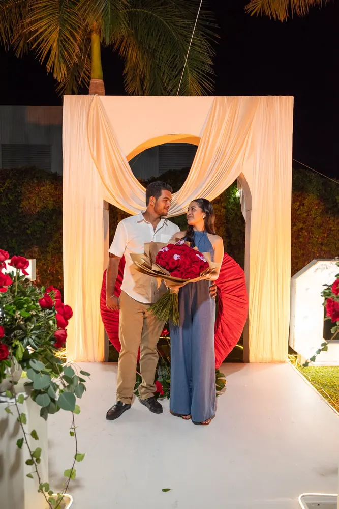 Estephany y Jorge con el ramo de rosas bajo el arco, el día de la pedida